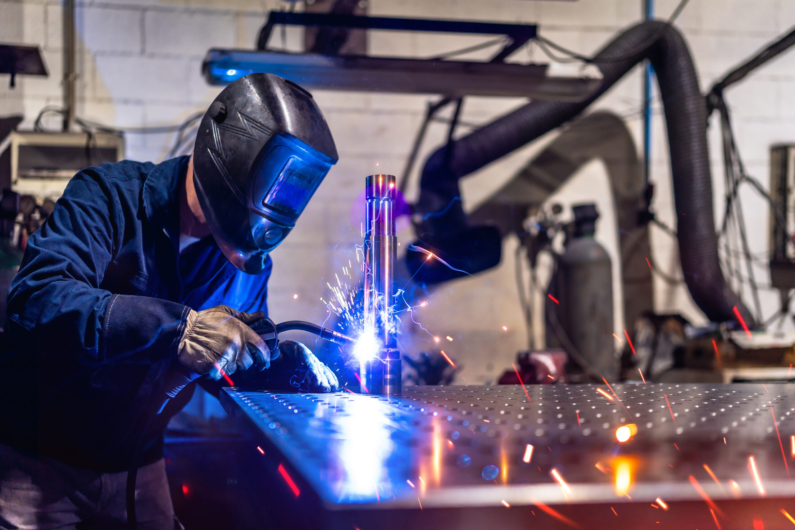 Man working in a factory welding pieces of metal