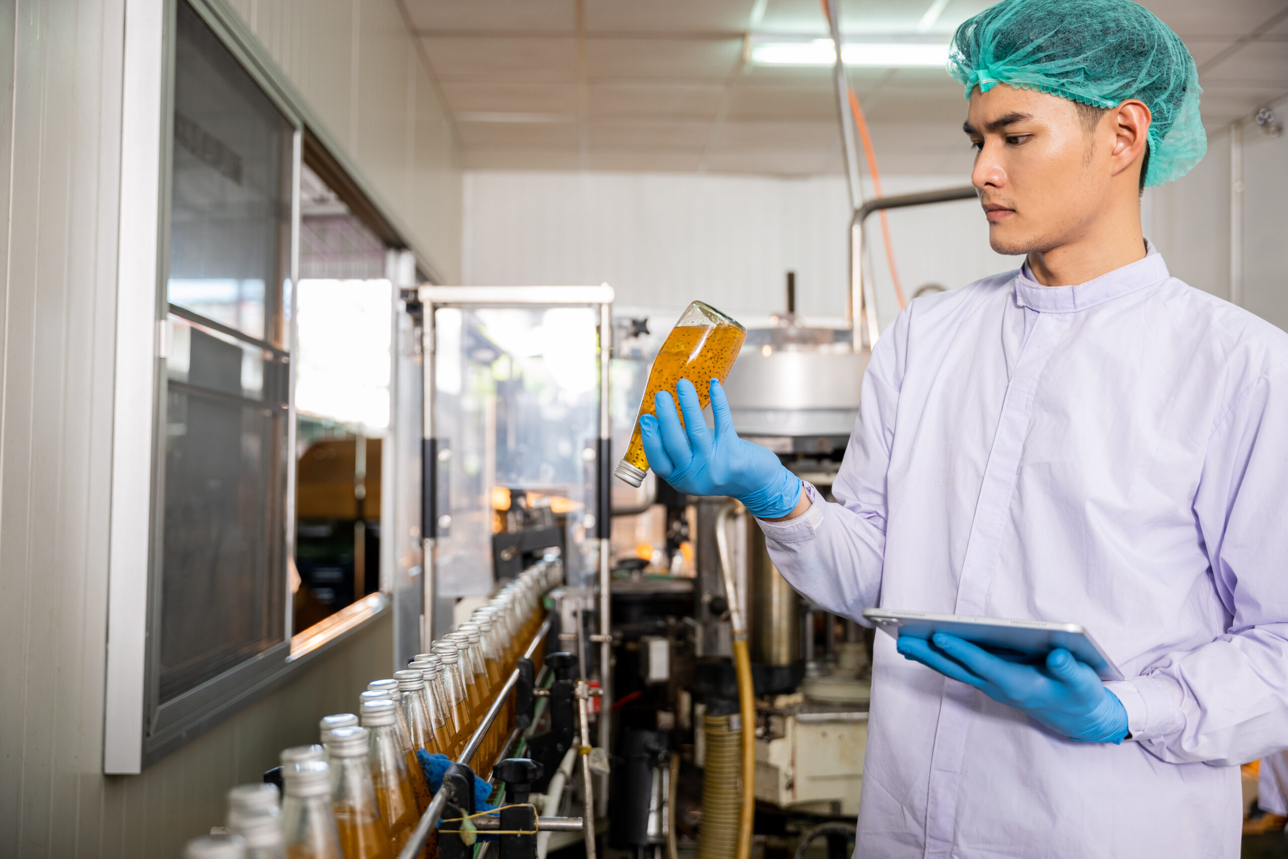 Quality control officer inspects beverage bottling factory line with tablet ensuring top-notch quality