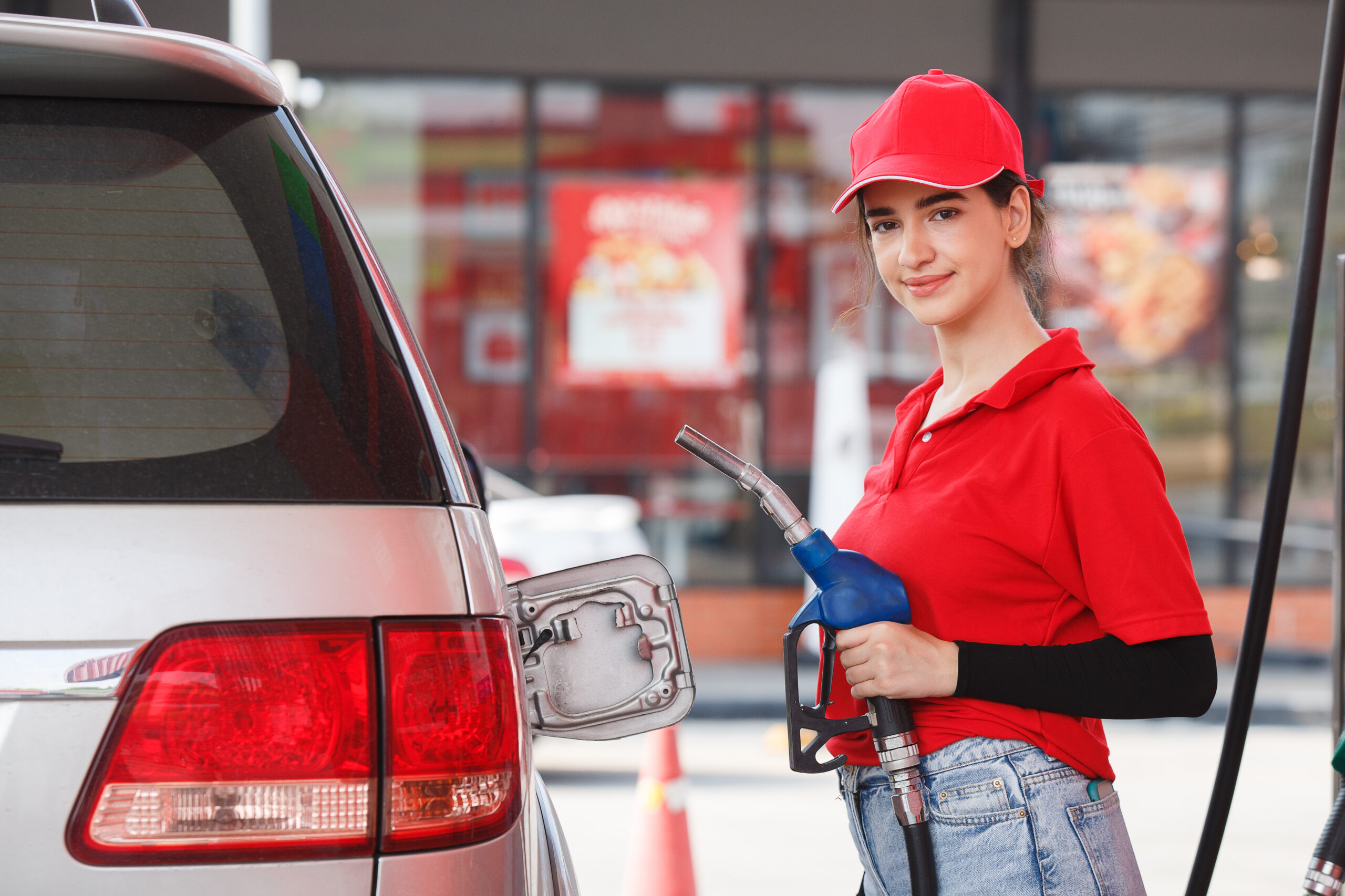 young caucasian woman red uniform holding fuel pump nozzle servi